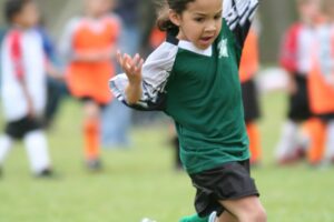 Child shooting the ball on a football field